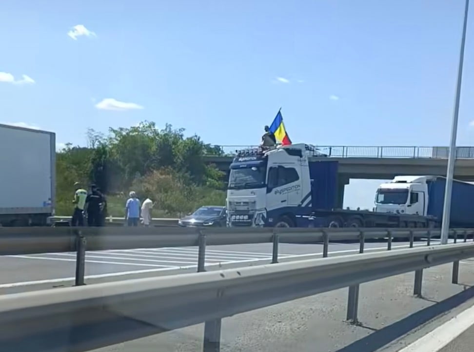 VIDEO Sensul către Bucureşti al A1, blocat – Un şofer a oprit vehiculul de mare tonaj de-a latul şoselei şi s-a urcat pe cabină, fluturând steagul României UPDATE Screenshot 2025 07 20 at 15.35.32